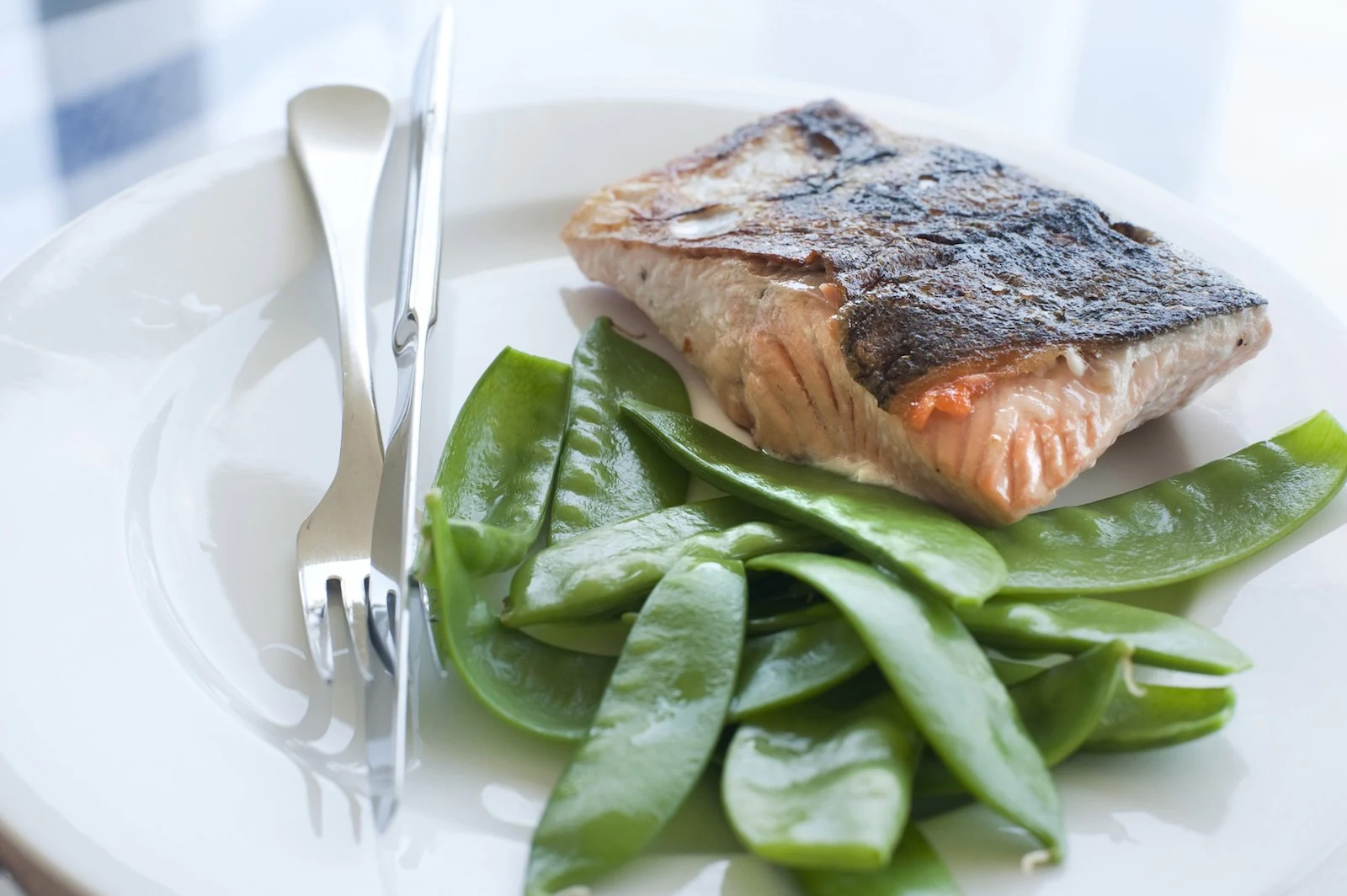 Gebratenes Lachsfilet auf grünen Zuckerschoten